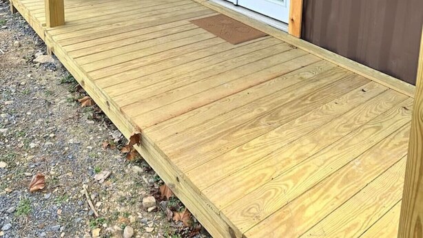 Una terraza de madera con dos puertas corredizas que dan a un porche cubierto.