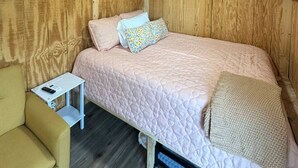 Una habitación acogedora con una cama, una mesita y una silla.