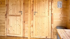 A wooden cabin interior with two doors, a sign reading "Hike", and a table.