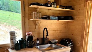 A compact kitchen with wooden cabinets, a sink, and a small countertop. There is a window providing a view of the outdoors.