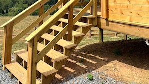 A wooden cabin with a wooden staircase leading to a covered entrance.