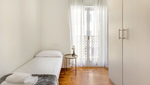 A bedroom with a bed, a small table with a lamp, a wardrobe, and a window with curtains. - GuestHost - Roomy and modern apartment of 108 sqm, for up to 7 people, on the 4th floor of a building with lift (NOT suitable for disabled people, some steps to access it). The property is located in the heart of Florence (Restricted-Traffic Area), just  (Florence)
