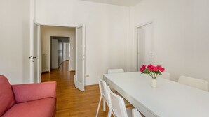 A modern, minimalistic room with a white table, a red sofa, and a vase of flowers. - GuestHost - Roomy and modern apartment of 108 sqm, for up to 7 people, on the 4th floor of a building with lift (NOT suitable for disabled people, some steps to access it). The property is located in the heart of Florence (Restricted-Traffic Area), just  (Florence)