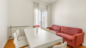 A room with a white table, white chairs, a red sofa, and a window with white curtains. - GuestHost - Roomy and modern apartment of 108 sqm, for up to 7 people, on the 4th floor of a building with lift (NOT suitable for disabled people, some steps to access it). The property is located in the heart of Florence (Restricted-Traffic Area), just  (Florence)