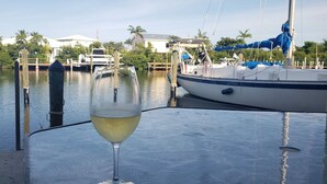 A glass of white wine on a table by a marina with boats and houses in the background. - Anchors Away- Beautiful condo w/ boat slip, boat ramp & Pool (Marathon)