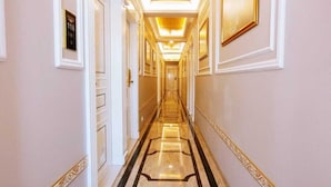 A long, narrow hallway with a marble floor and gold accents. - Anant Palace Hotel (Navi Mumbai)