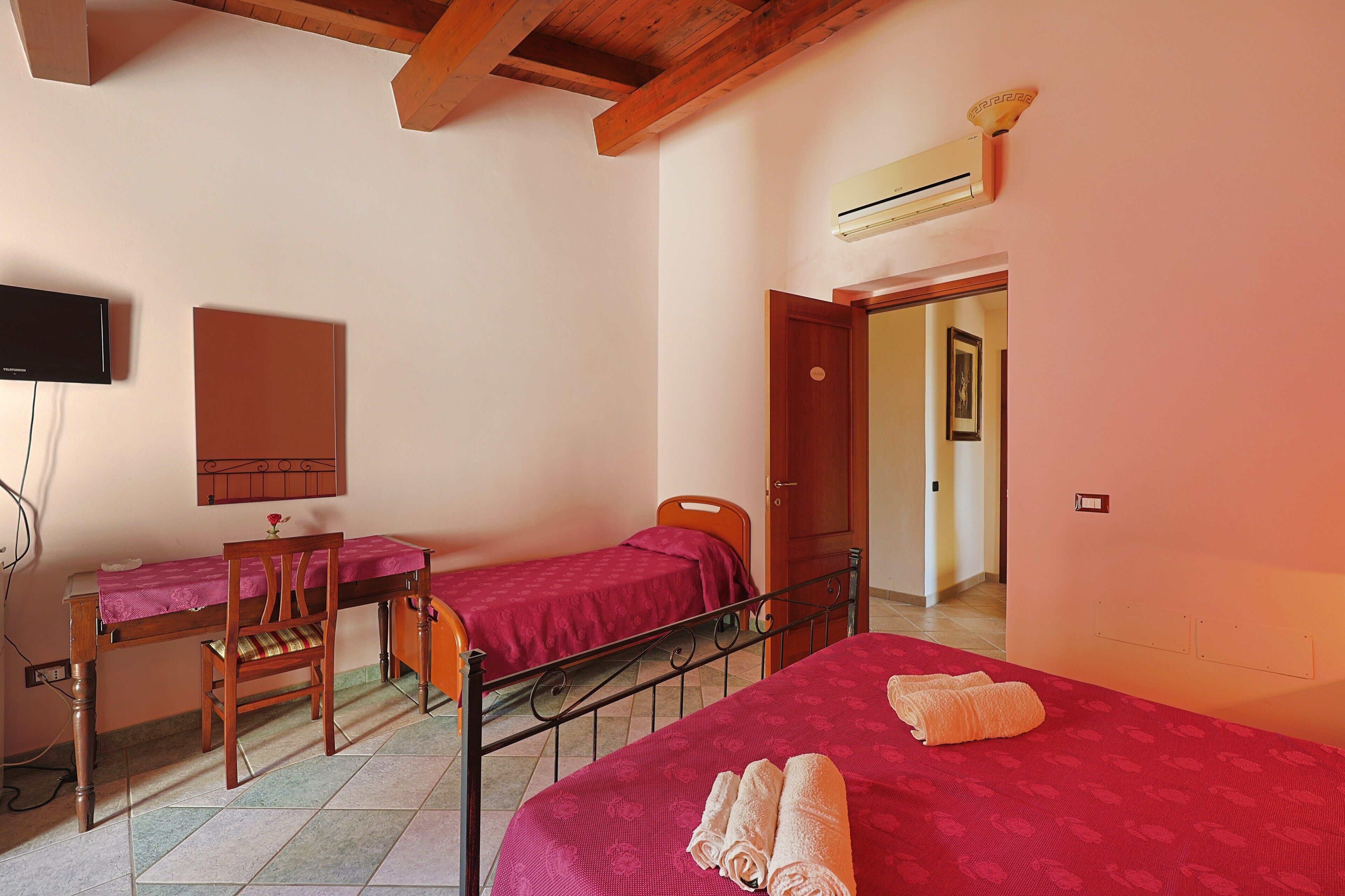 A room with two beds, a desk, a chair, and a television.
