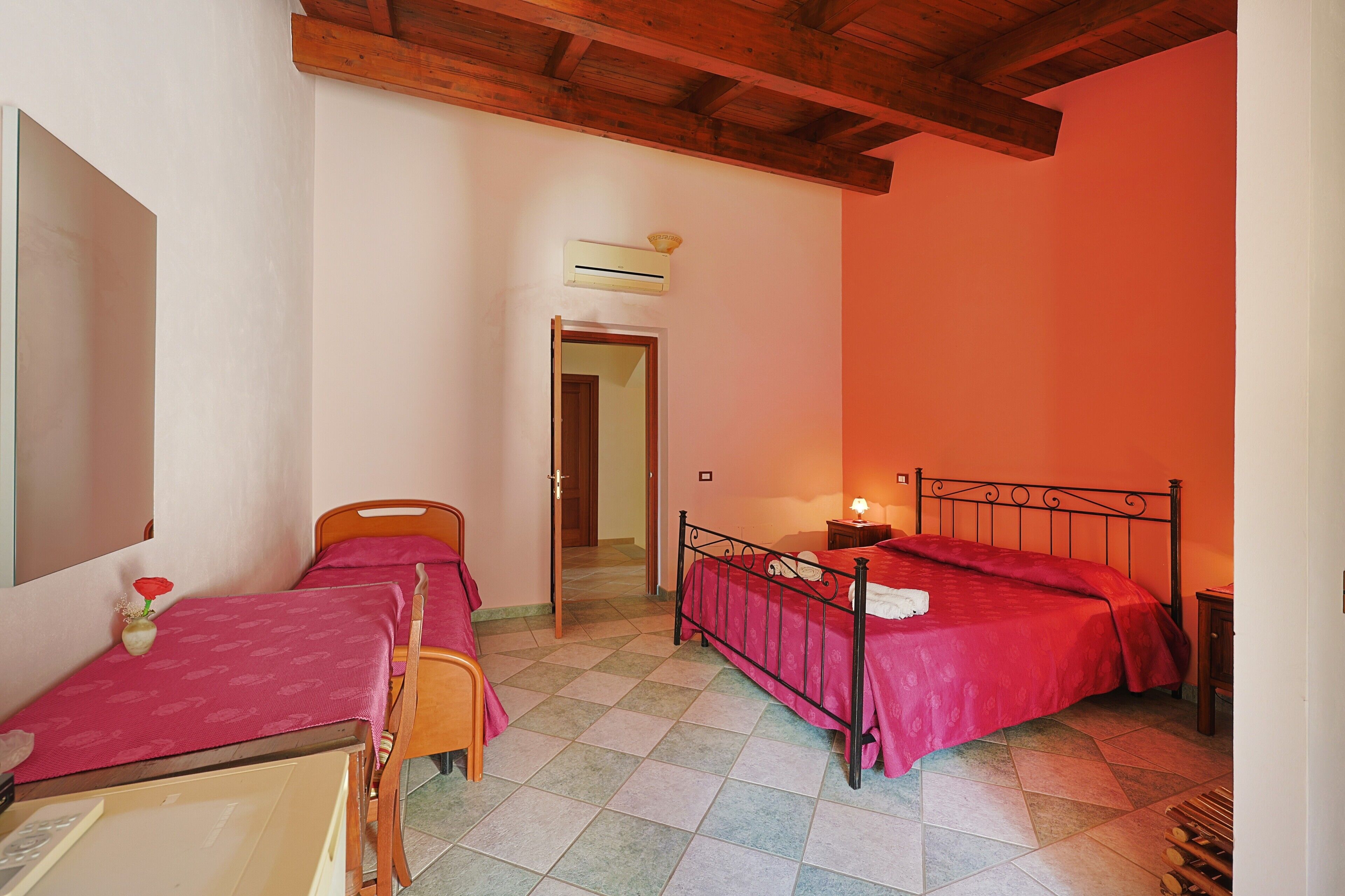 Ein Schlafzimmer mit zwei Betten, Holzboden, Fliesenboden und einer Tür zu einem anderen Raum.