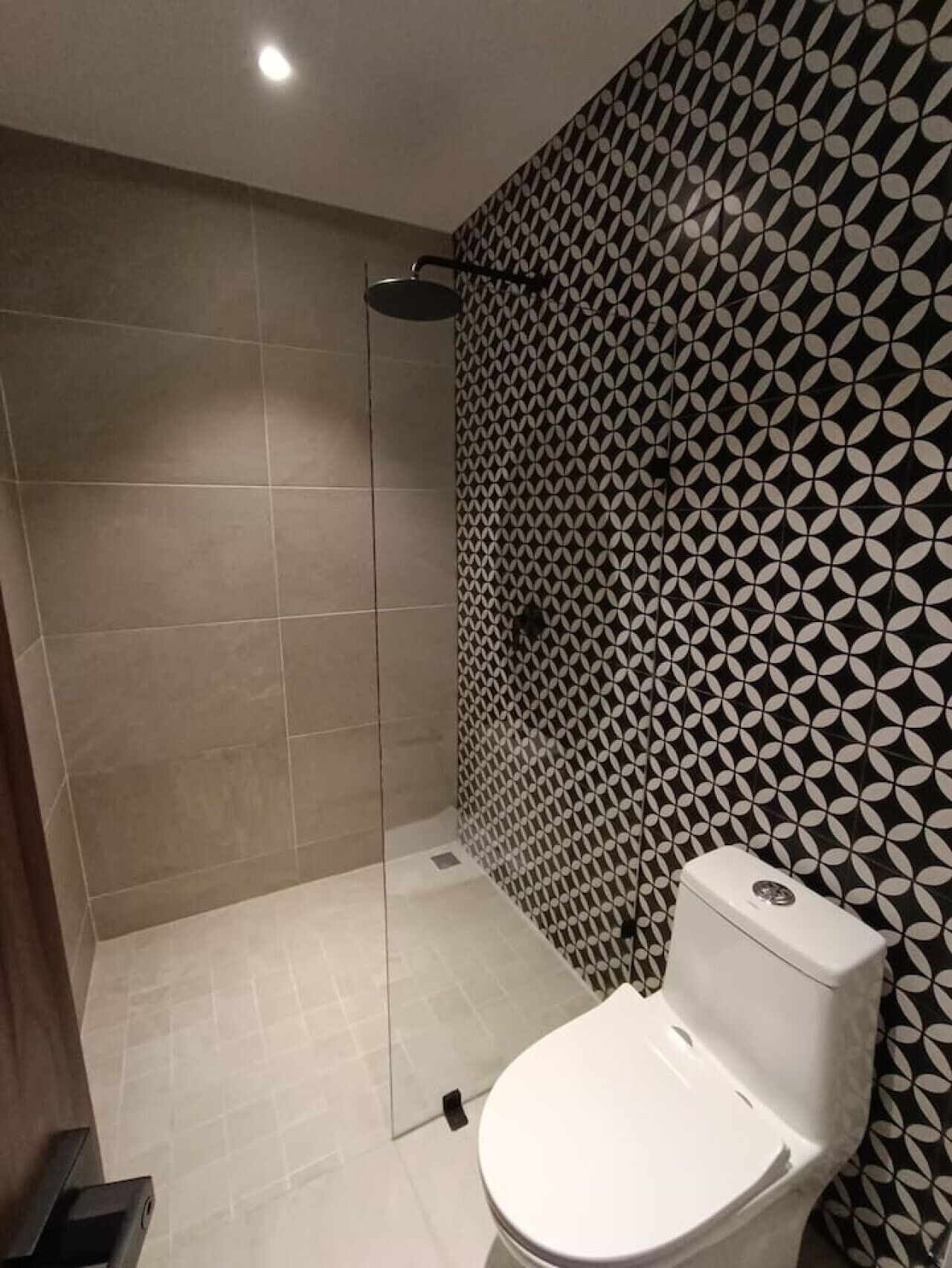 A bathroom with a patterned wall, a toilet, and a shower area.