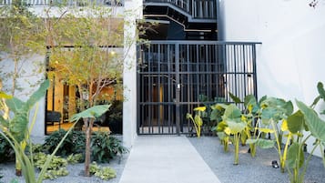 Un edificio moderno con entrada protegida, un sendero estrecho y varias plantas.