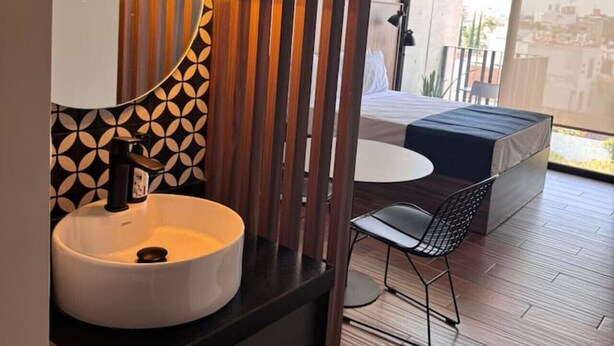 Une salle de bain moderne avec un grand miroir, un lavabo rond et deux lampes suspendues.
