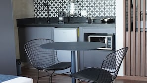 Una cocina compacta con comedor, diseño moderno, salpicadero de azulejos, horno empotrado y un refrigerador pequeño.