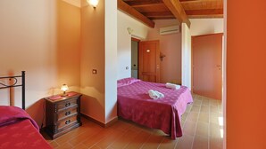 A bedroom with a bed, a nightstand, a dresser, and a door leading to another room.