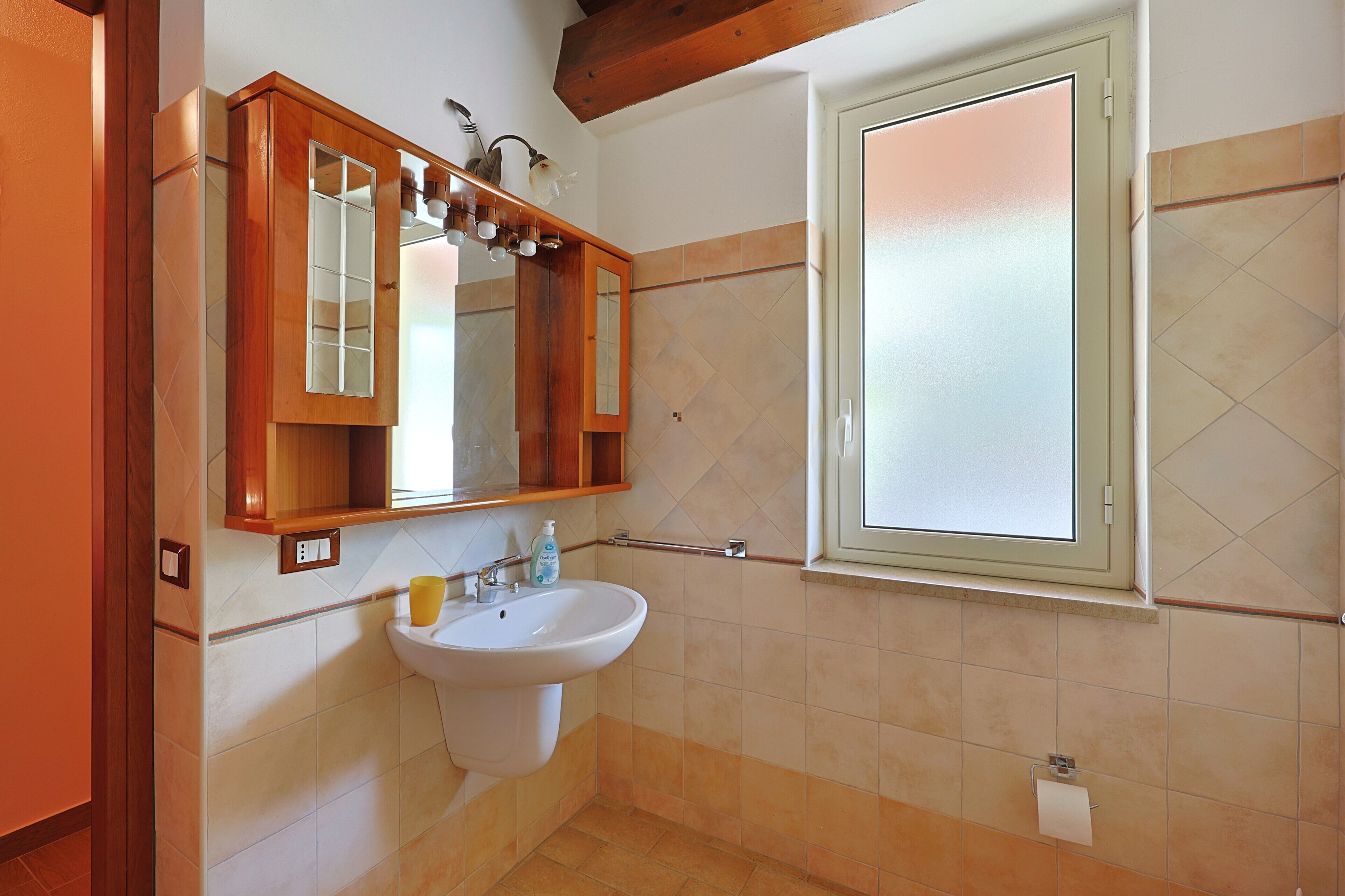 Une salle de bain avec un lavabo, un miroir et une fenêtre.