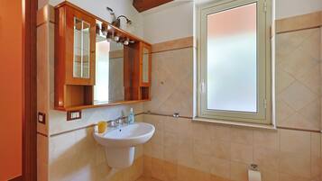 Une salle de bain avec un lavabo, un miroir et une fenêtre.
