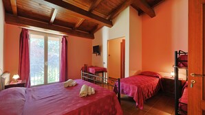 A bedroom with two beds, a wooden ceiling, a window with curtains, a TV, and a door.
