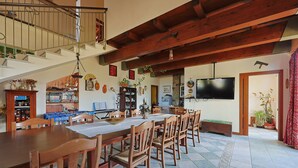 A dining area with a long wooden table, multiple chairs, and a staircase leading to an upper level.