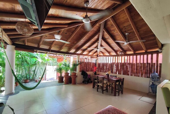 Un'area patio coperta con soffitto in legno, ventilatori a soffitto e piante in vaso.