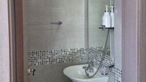 Un baño moderno con ducha, lavamanos y espejo.