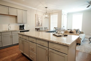 A modern kitchen with a central island, built-in cabinets, and a dining area with a table and chairs. - Stay At The Mill In Oxford (Oxford)