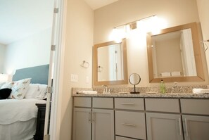 A hotel bathroom with a double sink, a large mirror, and a bed with white linens. - Stay At The Mill In Oxford (Oxford)