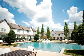 A pool area with lounge chairs and a building with multiple windows.