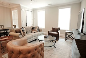 A living room with a sofa, armchair, coffee table, and a television. - Stay At The Mill In Oxford (Oxford)