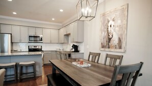 A modern kitchen with white cabinets, a wooden dining table, and a chandelier. - Stay At The Mill In Oxford (Oxford)
