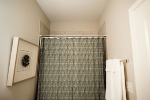 A bathroom with a shower curtain, a framed picture on the wall, and a towel rack. - Stay At The Mill In Oxford (Oxford)