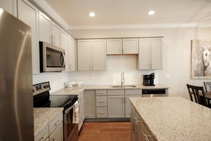 A modern kitchen with stainless steel appliances, light-colored cabinetry, and a granite countertop. - Stay At The Mill In Oxford (Oxford)