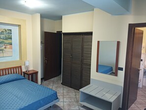 A bedroom with a bed, a wardrobe, a mirror, and a small table with a lamp. - Residence Hotel Azzurro (L'Aquila)