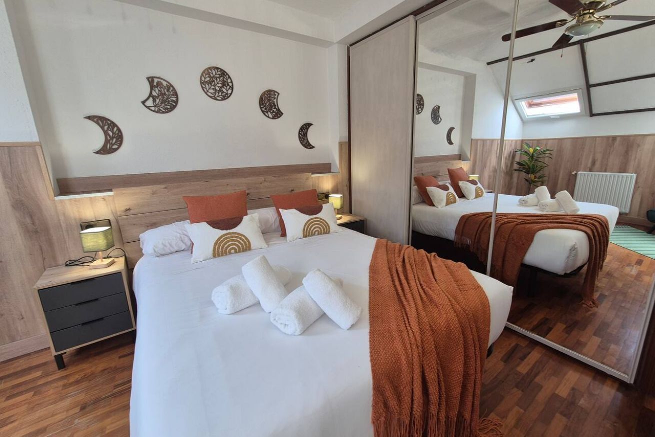 Quarto de hotel com cama grande, mesas de cabeceira, espelho e obras de arte na parede.