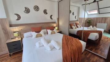 Quarto de hotel com cama grande, mesas de cabeceira, espelho e obras de arte na parede.