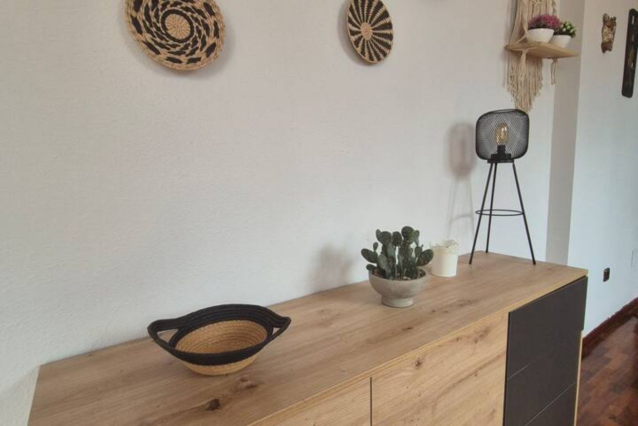 A wooden console table with a woven basket, a potted plant, and a floor lamp.