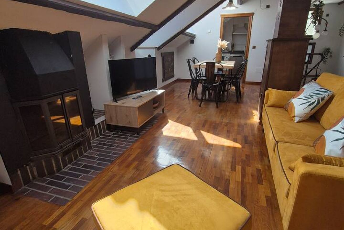 A living room with a fireplace, a TV, a dining area, and a yellow sofa.