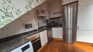 A compact kitchen with a washing machine, microwave, stainless steel refrigerator, and a tiled floor. - 1C152: Renovated Triplex in Cimadevilla (Gijón)