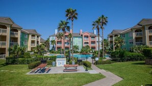 A multi-story hotel with balconies, a swimming pool, and palm trees.