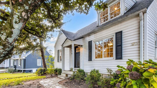 A two-story house with a stone pathway leading to the front door, surrounded by greenery and a well-maintained lawn. - Charming 3BR Retreat in Chamblee (Chamblee)
