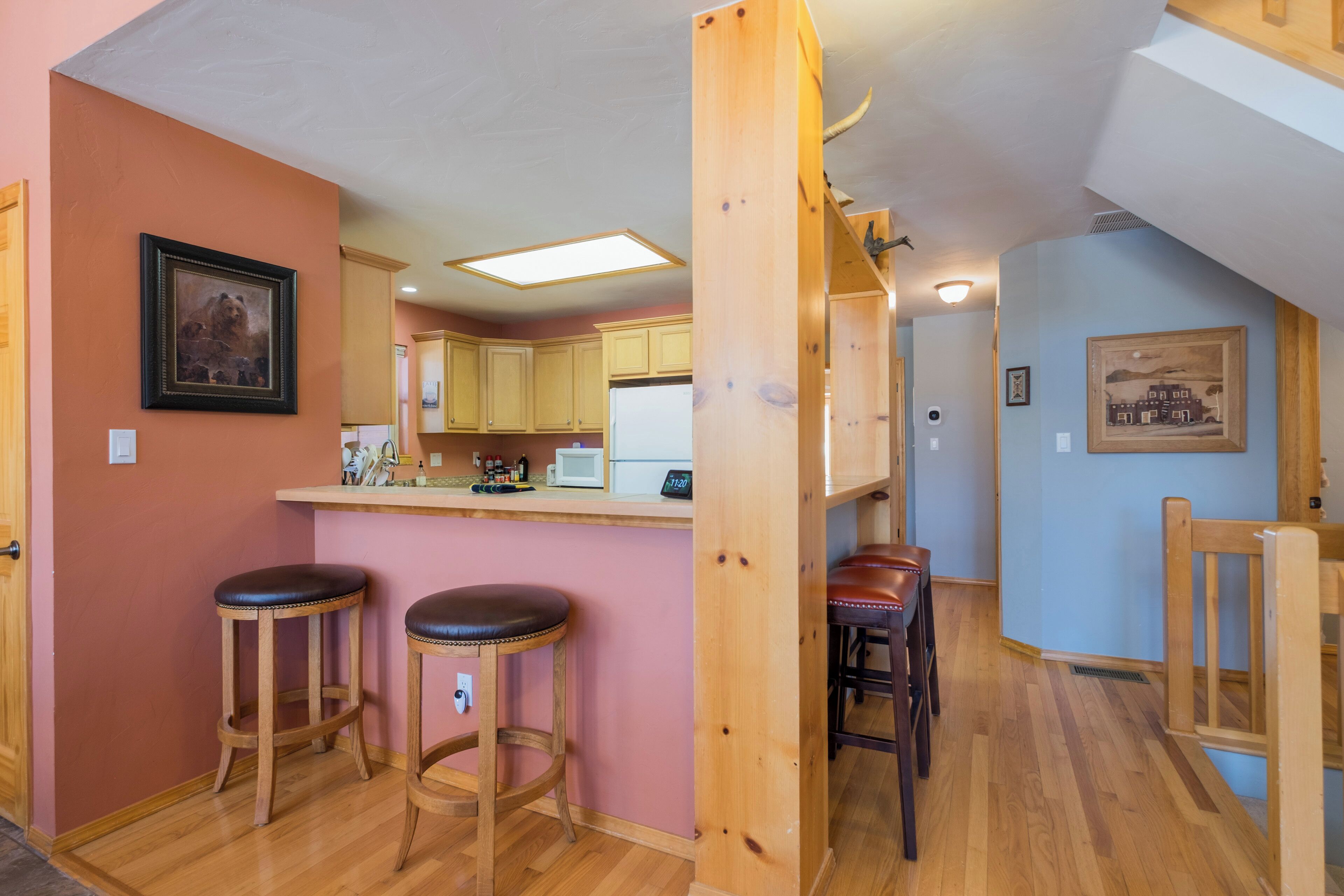A kitchen with wooden stools, a bar area, and a dining table.