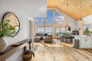 Un vaste espace de vie agrémenté d’une grande fenêtre, d’un plancher en bois et d’un coin salon confortable.
