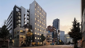 A modern urban street with multi-story buildings, including a hotel with a prominent facade and balconies. - Four Points Flex By Sheraton Tokyo Higashi Kanda (Tokyo)