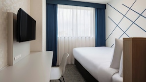 A hotel room with a bed, a desk, a chair, a TV, and a window with curtains. - Four Points Flex By Sheraton Tokyo Higashi Kanda (Tokyo)