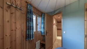 Habitación con paneles de madera, una cama, un radiador y una puerta que da a otra habitación.
