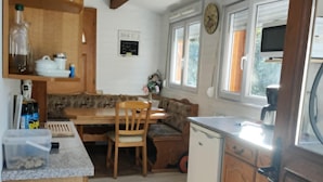 Una cocina compacta con muebles de madera, una mesa de comedor y un refrigerador pequeño.