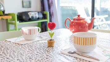 Ein Tisch mit einer Tischdecke mit Muster, eine rote Teekanne und zwei Tassen mit Streifenmuster.