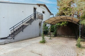 A building with a staircase, a covered outdoor area, and a paved courtyard.
