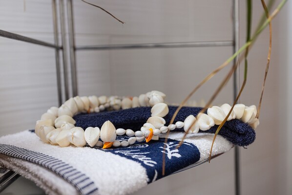 A shelf with a beaded necklace and a blue and white patterned towel.