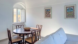 A dining area with a round table and chairs, a sofa, and two framed artworks on the wall.