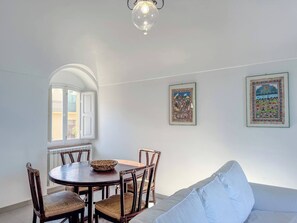 Un comedor con una mesa redonda y sillas, un sofá y dos obras de arte enmarcadas en la pared.
