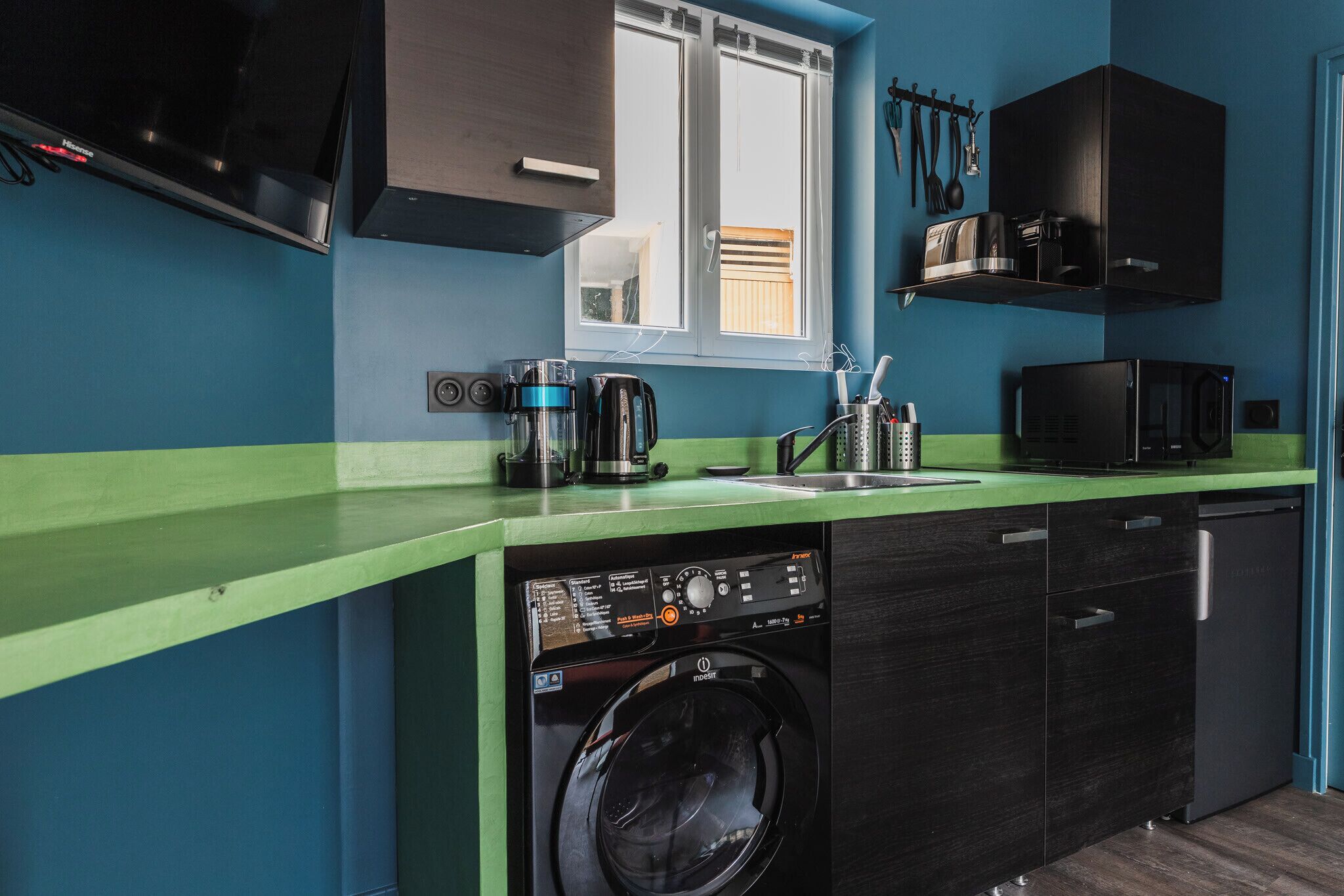 A compact kitchen with a washing machine, a coffee maker, and a microwave.